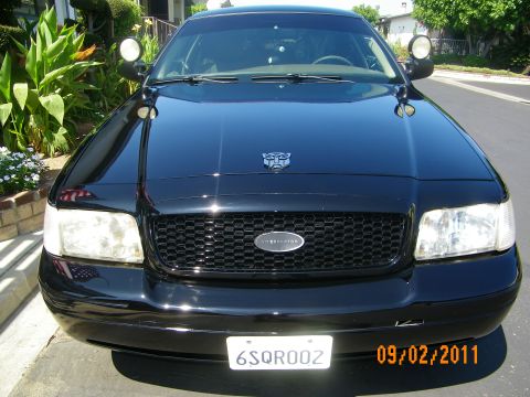 2003 Ford Crown Victoria - Front view of a black police car, possibly a Ford Crown Victoria, with an Interceptor badge and a Transformers logo on the hood.