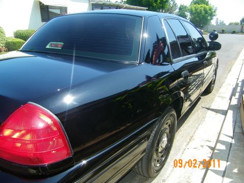 2003 Ford Crown Victoria - A black 2003 Ford Crown Victoria is shown from the rear quarter angle, highlighting its clean, waxed finish.