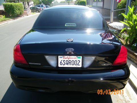 2003 Ford Crown Victoria - Straight rear view of a black sedan with Police Interceptor and Limited badges, plate 6SQR002.