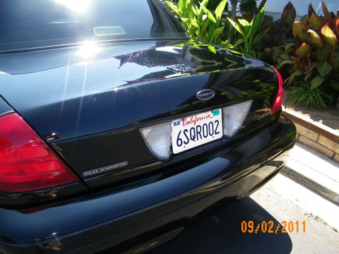 2003 Ford Crown Victoria - Close trunk view of a black sedan showing Police Interceptor lettering and California plate 6SQR002.