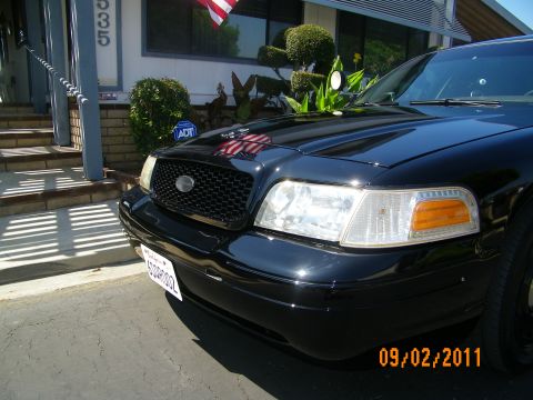 2003 Ford Crown Victoria - Close front view of a black sedan showing mesh grille, clear headlight and Transformers hood decal.