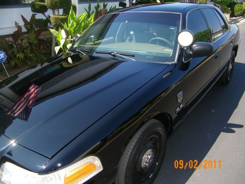 2003 Ford Crown Victoria - Front-side view of a black Ford sedan showing windshield, side mirror and Transformers fender decal.