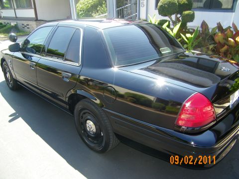 2003 Ford Crown Victoria - Rear-side three-quarter of a black Ford sedan on body-color steel wheels with tinted glass.