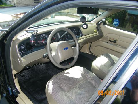 2003 Ford Crown Victoria - Interior of a black sedan with parchment cloth seats, Ford steering wheel and column shifter.