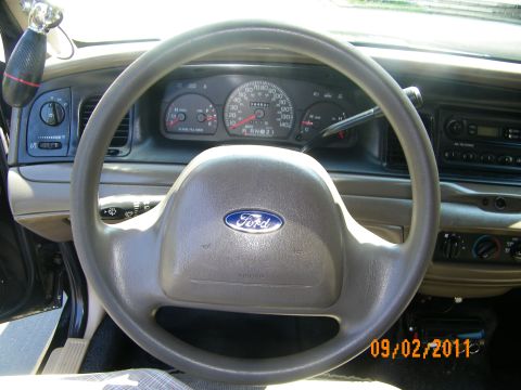 2003 Ford Crown Victoria - Driver view of a Ford-badged steering wheel and gauge cluster with column-mounted shifter.