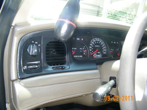 2003 Ford Crown Victoria - Angled dash view of a black sedan showing headlight controls, center vent and instrument cluster.