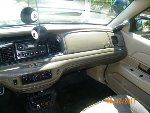 2003 Ford Crown Victoria - Passenger-side dash showing glovebox, lower vent and Crown Victoria badge with hanging 8-ball decorations