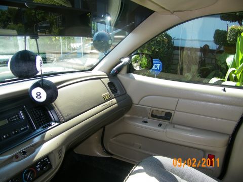 2003 Ford Crown Victoria - Interior shot toward passenger door armrest and window with grab handle and 8-ball hangers on mirror