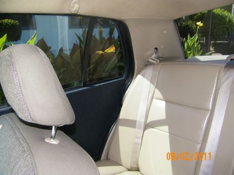 2003 Ford Crown Victoria - Back seat view showing two-tone tan leather rear cushion, seatbelt and rear door pillar