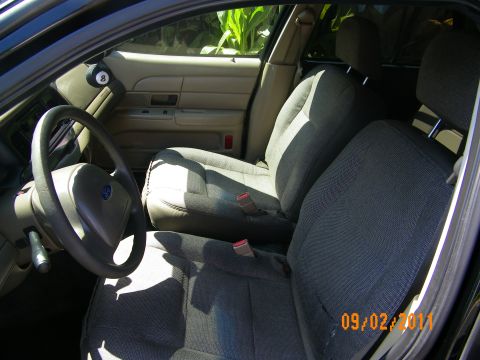2003 Ford Crown Victoria - Driver area showing Ford-logo airbag, split bench seats in gray fabric and tan dashboard