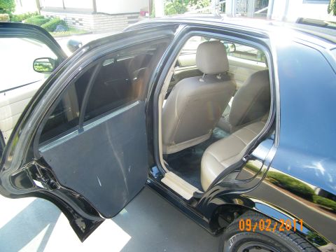 2003 Ford Crown Victoria - Rear passenger door swung open revealing the back seats with black steel wheel at the sill
