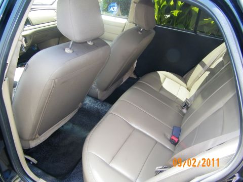 2003 Ford Crown Victoria - Back bench upholstered in beige leather viewed past the front seats with buckles fastened