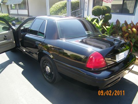 2003 Ford Crown Victoria - Rear quarter of a black full-size sedan on steelies with driver door open in a driveway