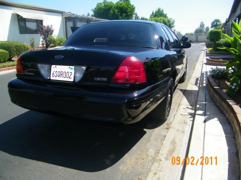 2003 Ford Crown Victoria - Rear of black full-size sedan showing taillights, Ford oval, Limited trim badge and CA plate