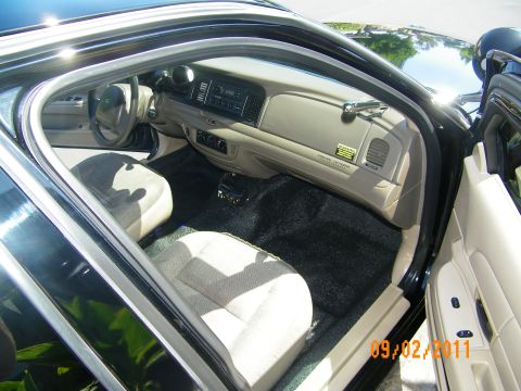 2003 Ford Crown Victoria - Wide interior shot through the front door showing beige cabin, dashboard and column shifter