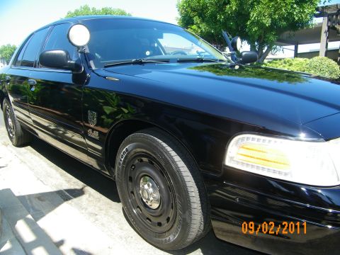 2003 Ford Crown Victoria - Front driver side of black sedan showing spotlight, hood, 4.6 emblem and black steelie