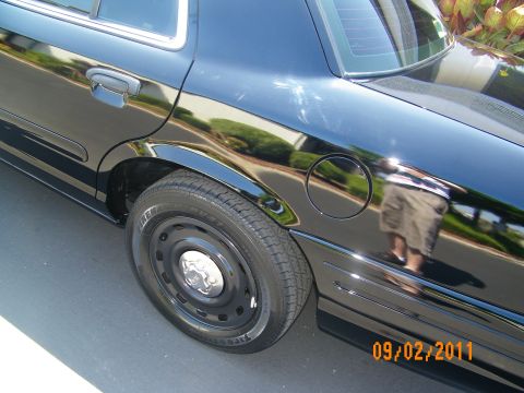 2003 Ford Crown Victoria - Detail of black sedan rear fender, fuel filler door and black steel wheel with chrome center cap.