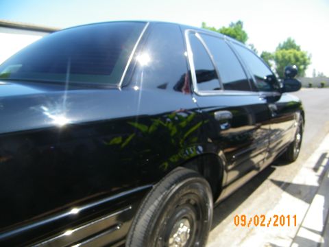 2003 Ford Crown Victoria - Reflective black paint on rear doors and tinted glass of a Crown Victoria, chrome trim and mirror visible.