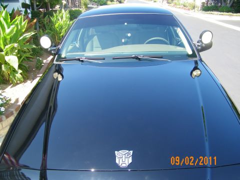 2003 Ford Crown Victoria - Front hood of a dark Crown Victoria showing an Autobot Transformers decal, wipers and pillar-mounted spotlights.