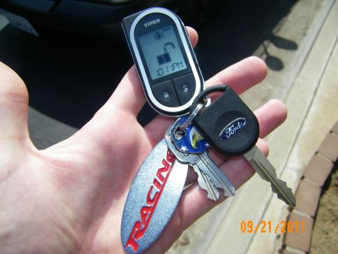 2003 Ford Crown Victoria - Close-up of a Viper alarm remote reading 10:11 PM beside a Ford-logo key and Ford Racing fob in a hand.