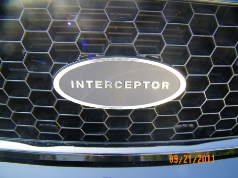 2003 Ford Crown Victoria - Detail of the chrome Interceptor badge set in a black honeycomb mesh grille on a Crown Victoria.