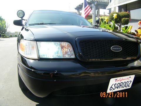 2003 Ford Crown Victoria - Angled front view of a black Crown Victoria headlight, Interceptor grille emblem and pillar spotlight.