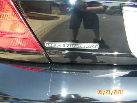 2003 Ford Crown Victoria - Chrome Police Interceptor emblem on the trunk of a black Crown Victoria, photographer reflected in paint.