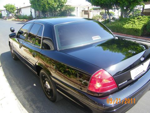 2003 Ford Crown Victoria - Glossy black Ford sedan shot from rear corner showing trunk, tail lights and Ford oval badge, dated 05/21/2011