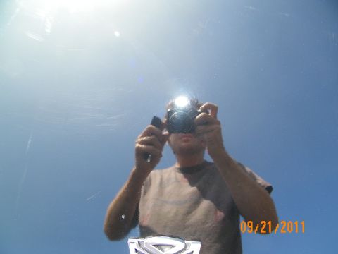 2003 Ford Crown Victoria - Mirror-finish black paint reflects a person photographing the car under sun glare and clear sky