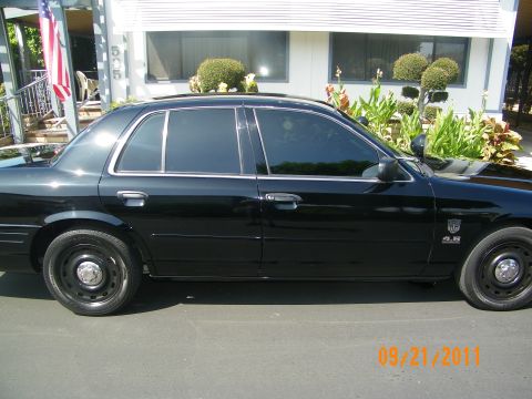 2003 Ford Crown Victoria - Black four-door sedan with tinted windows and black steel wheels shown in full side view