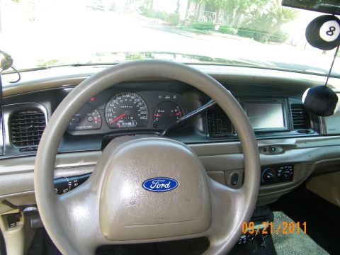 2003 Ford Crown Victoria - Interior view of Ford sedan dashboard, tan trim, gauges, eight-ball mirror hanger and aftermarket screen