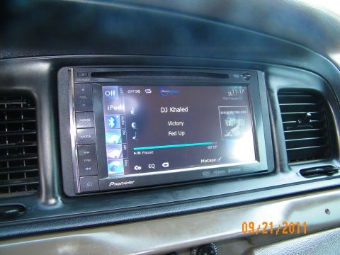 2003 Ford Crown Victoria - Aftermarket Pioneer screen showing iPod playback of DJ Khaled, mounted in tan vehicle dashboard