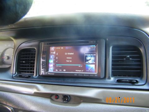 2003 Ford Crown Victoria - In-dash Pioneer media screen showing album art and track info, surrounded by vents and gauges