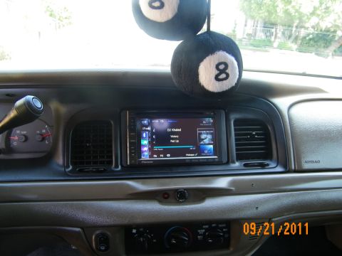 2003 Ford Crown Victoria - Aftermarket screen in tan dashboard with eight-ball dice hanging and Airbag-labeled passenger panel