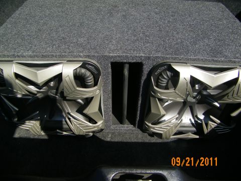 2003 Ford Crown Victoria - Pair of silver subwoofer drivers in a slot-ported box, Kicker branding visible on one cone