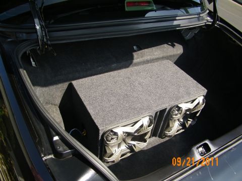 2003 Ford Crown Victoria - Sedan trunk with gray subwoofer enclosure holding two woofers, trunk hinges and liner visible