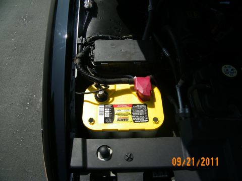 2003 Ford Crown Victoria - Yellow Optima battery seated in the engine bay with a red positive terminal cover.