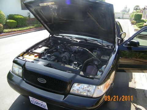 2003 Ford Crown Victoria - Black Crown Victoria Police Interceptor parked with hood raised showing the intake, plate 6SQR002.