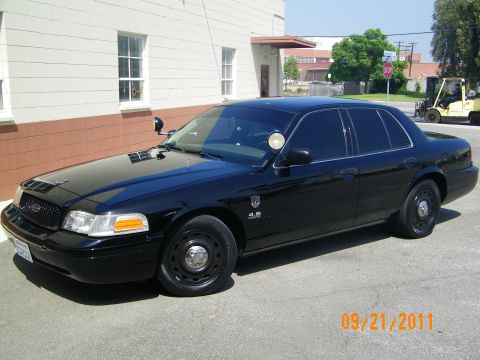 2003 Ford Crown Victoria - Front three-quarter of a black 4.6 Crown Victoria with blacked steel wheels and spotlight.