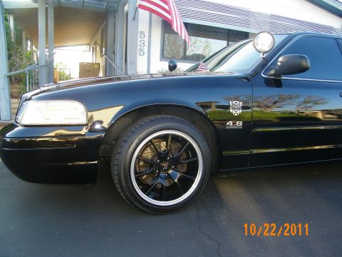 2003 Ford Crown Victoria - Fender detail of a black sedan wearing a 4.6 badge and an Autobot decal over a black wheel.
