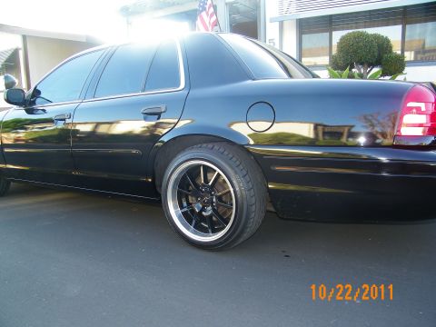 2003 Ford Crown Victoria - Rear three-quarter of a lowered black Crown Victoria showing fuel door and rear wheel.