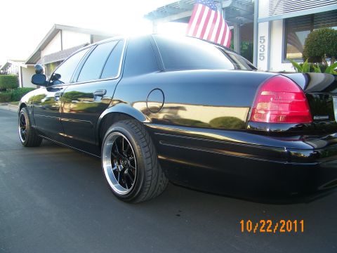 2003 Ford Crown Victoria - Black Crown Victoria rear quarter on dark wheels near a building marked 535.