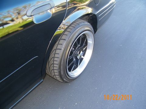 2003 Ford Crown Victoria - Rear wheel and door of a black sedan with reflective paint shot low to the ground.