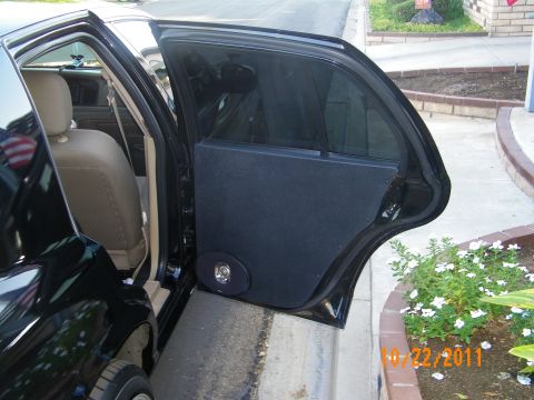 2003 Ford Crown Victoria - Open rear door with mounted speaker enclosure photographed beside a planted curb