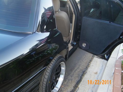 2003 Ford Crown Victoria - Glossy black sedan flank with polished-lip wheels and a rear door audio enclosure