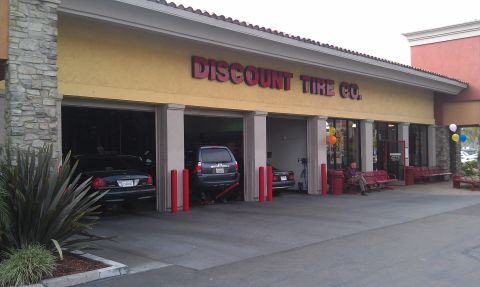 2003 Ford Crown Victoria - Discount Tire Co building exterior with cars in open bays and a waiting bench