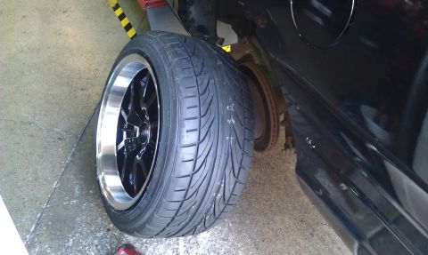 2003 Ford Crown Victoria - Low-profile tire on a black aftermarket wheel resting near a car's brake rotor