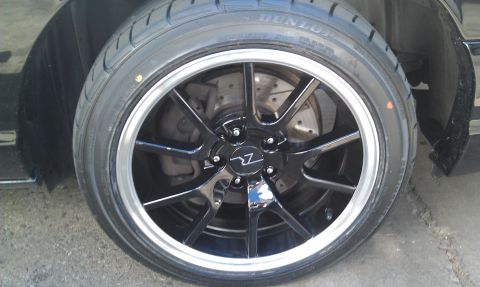 2003 Ford Crown Victoria - Mounted black wheel on a Dunlop tire showing the brake rotor behind the spokes