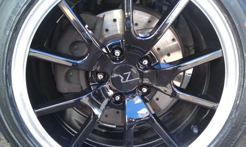 2003 Ford Crown Victoria - Detailed view of a glossy black-and-chrome wheel over a drilled brake disc