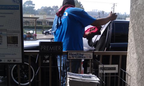 2003 Ford Crown Victoria - Attendant wiping down a dark vehicle next to Premier and Healthy Times racks